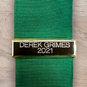 image showing gold medal bar with green ribbon on wood background